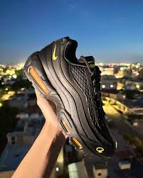 Close-up of the Corteiz x Nike Air Max 95 'Honey Black' and 'Rules the World' sneakers showcasing colorways, materials, and toggle lacing.