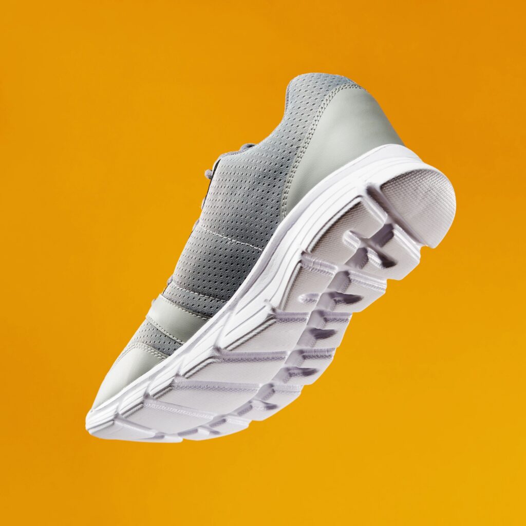 Low angle bottom view of sports running and fitness shoe, sneaker on orange background